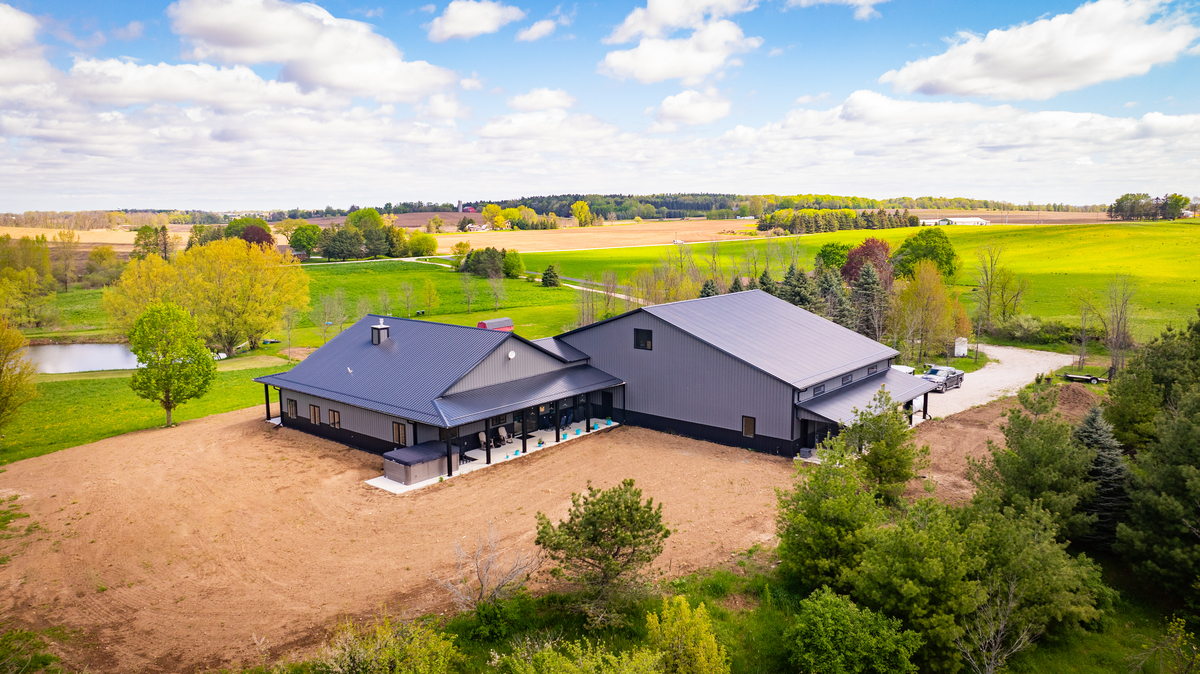 modern dark gray barndominium-style house with covered patio in rural area