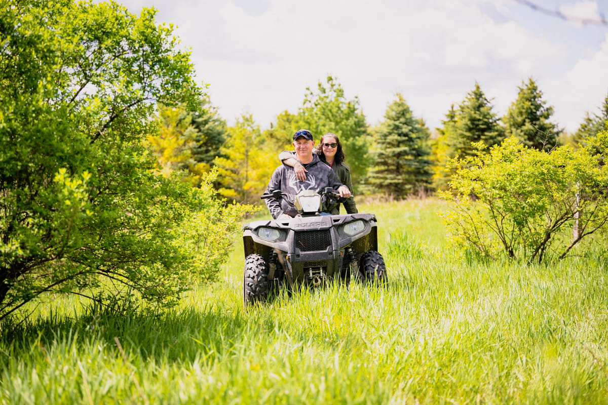Three adults talking around an ATV in a field