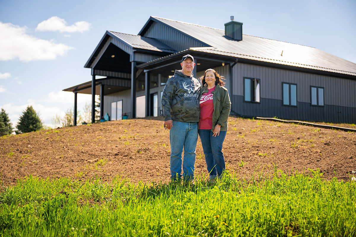 The Ravns, husband and wife, standing in front of new barndominium