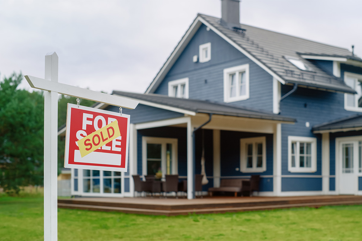 for sale sign in front of a blue house