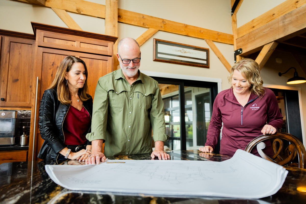 Couple reviewing home building plans with a Compeer Home loan officer at a table.