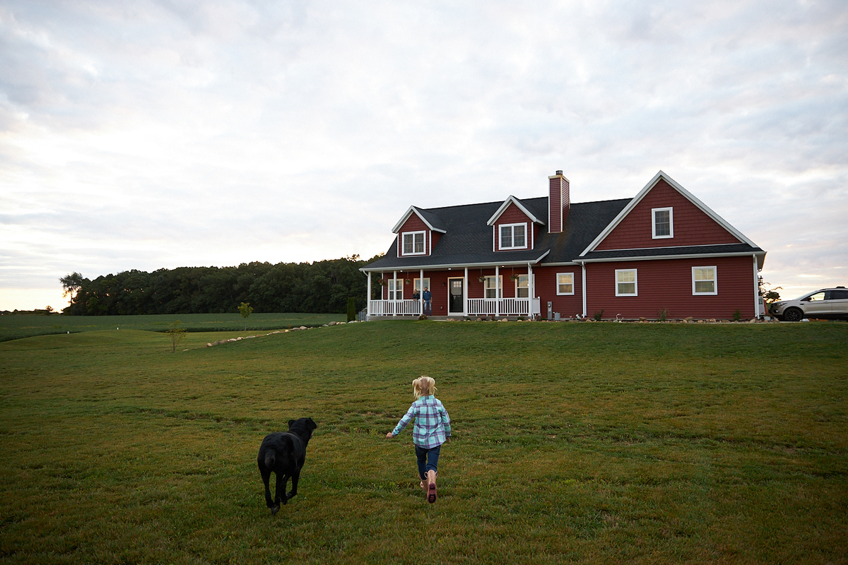 farmhouse with wraparound porch and horses in the yard