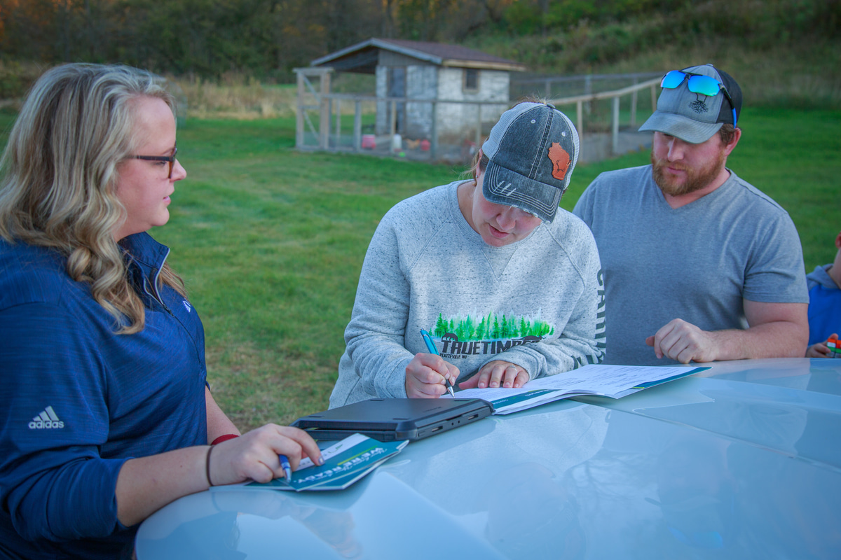 couple signing loan conversion on hood of truck