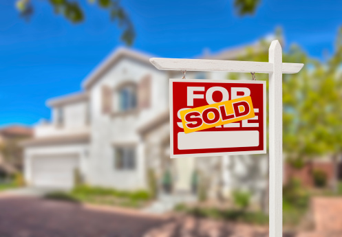 A “SOLD” sign in front of a modern white home