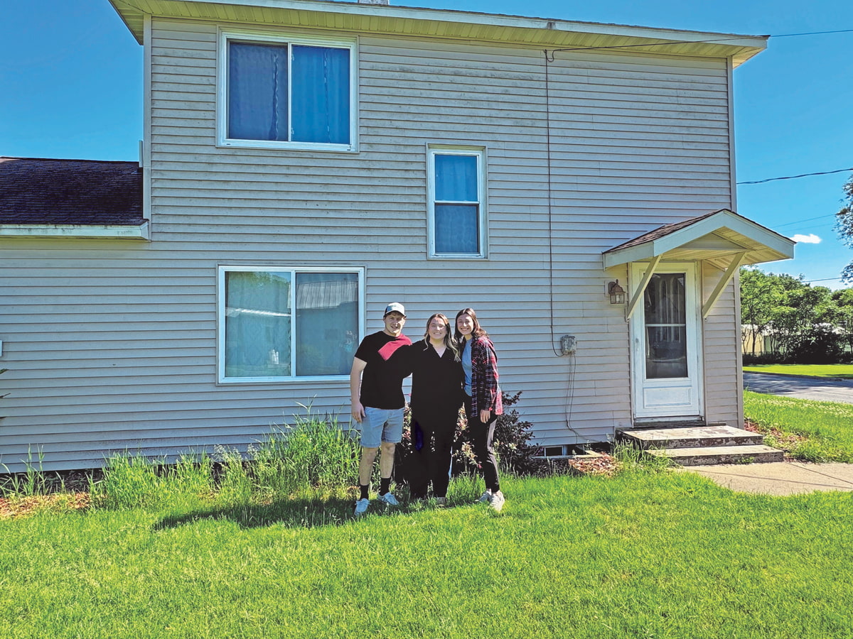 young couple stands in front of their first home after securing a first-time homebuyer loan mortgages 