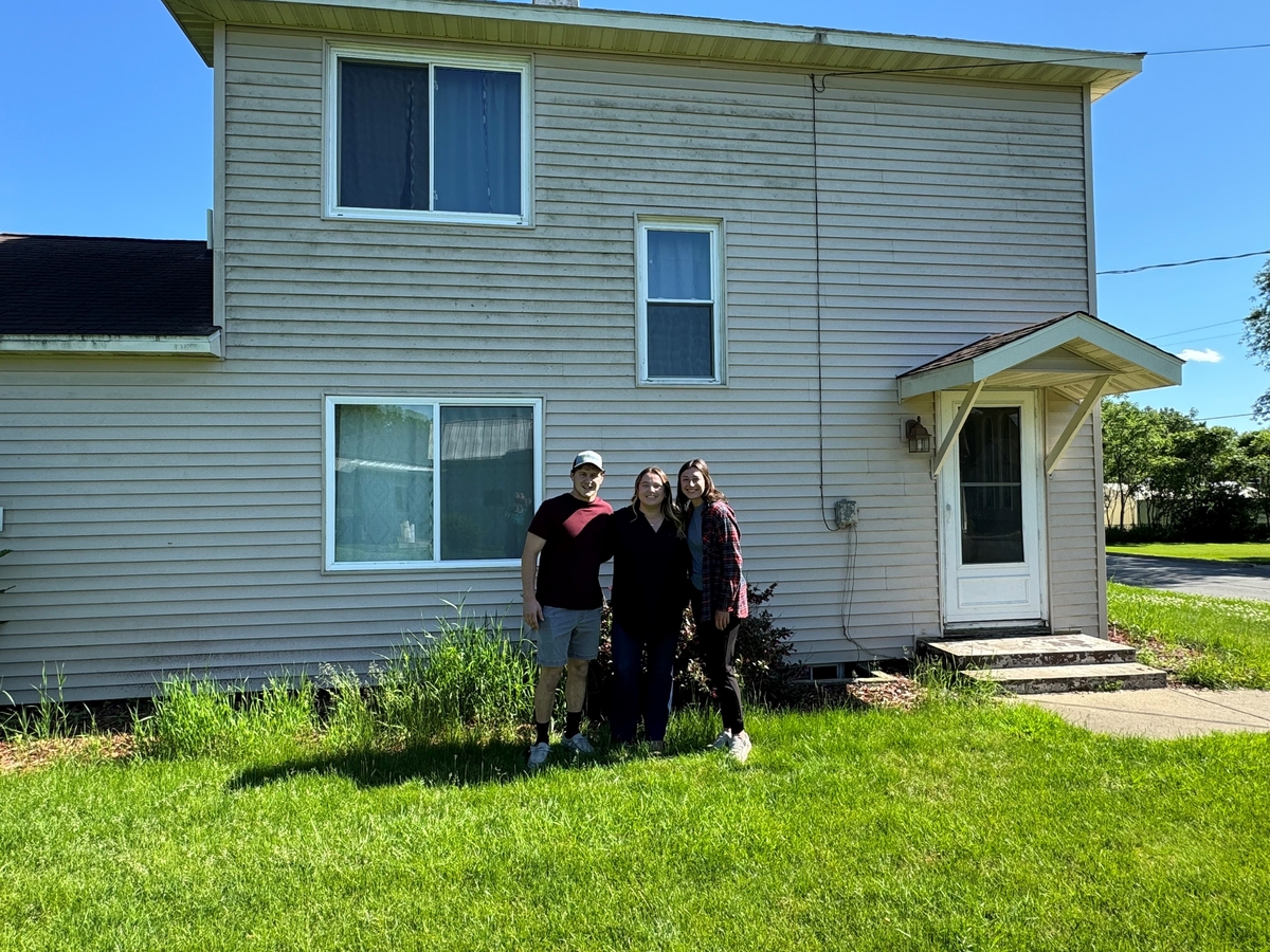 young couple stands in front of their first home after securing a first-time homebuyer loan mortgages 