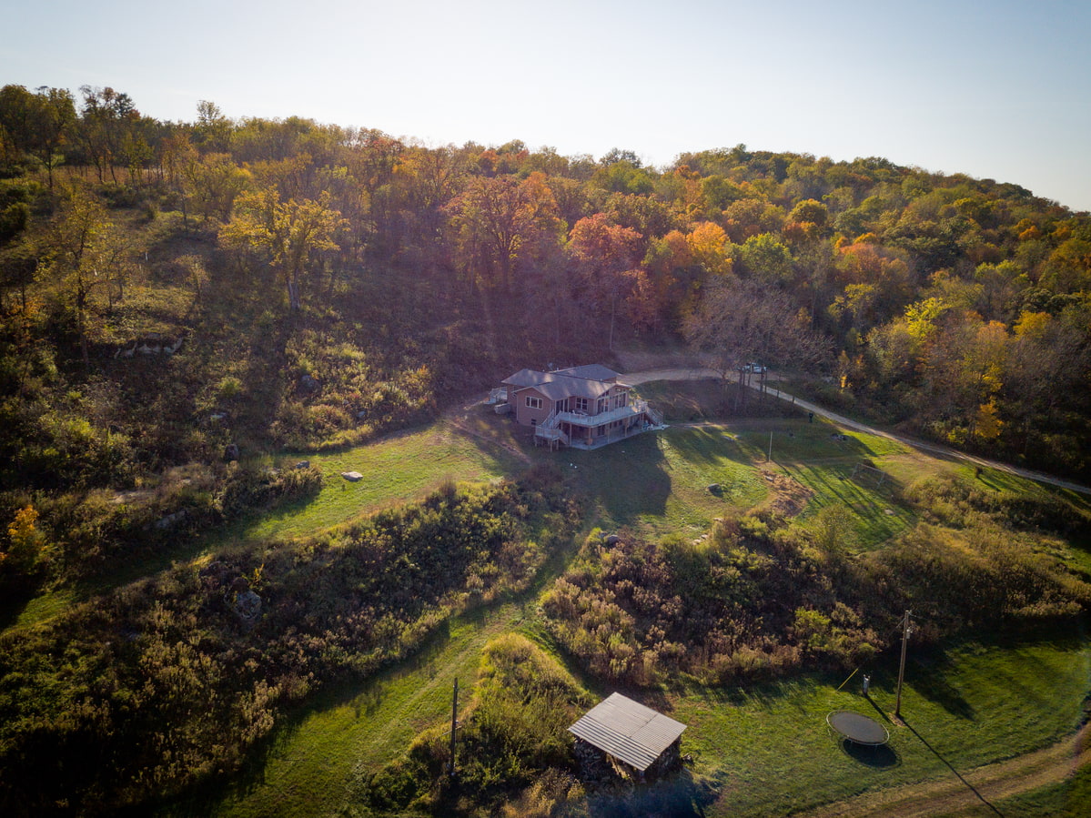 A rural home surrounded by trees with colorful fall foliage on a sunny day.