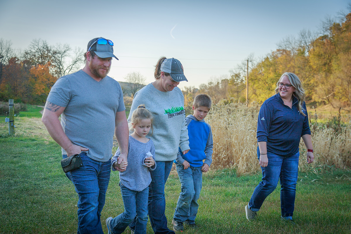 Three adults and two children walking on a grassy lawn
