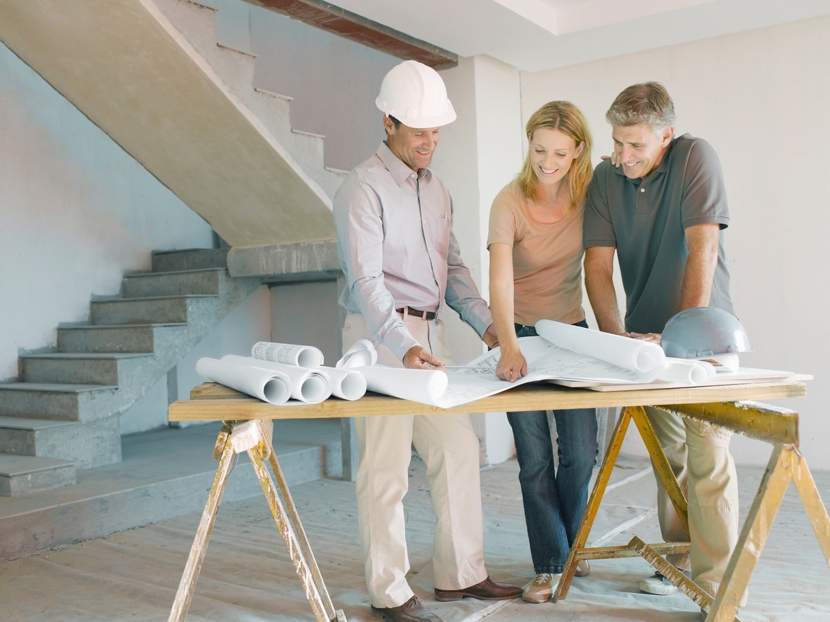 Homeowners and contractor discussing sustainable renovation plans inside a home under construction.