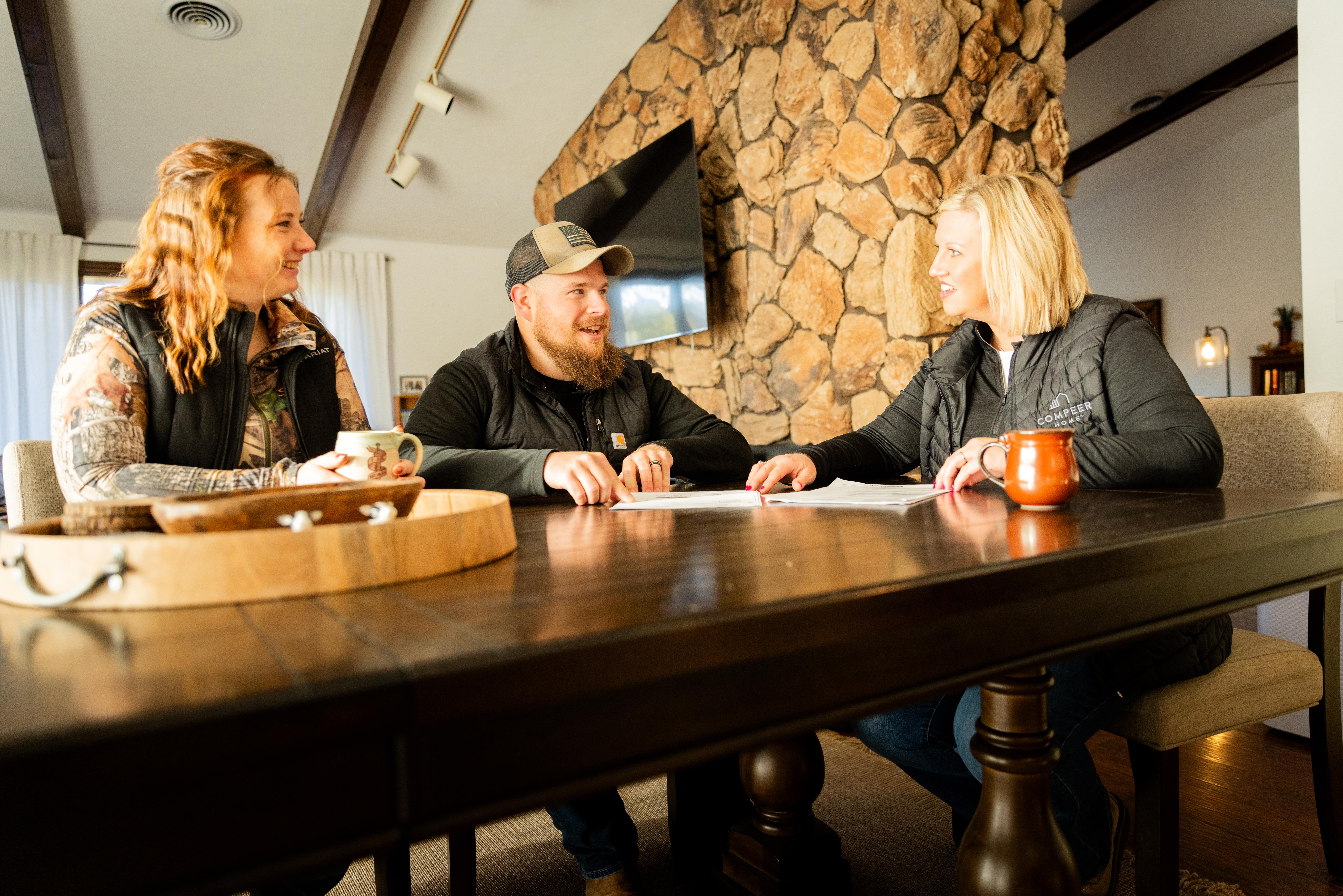 Couple meeting with loan officer at kitchen table, smiling and reviewing paperwork