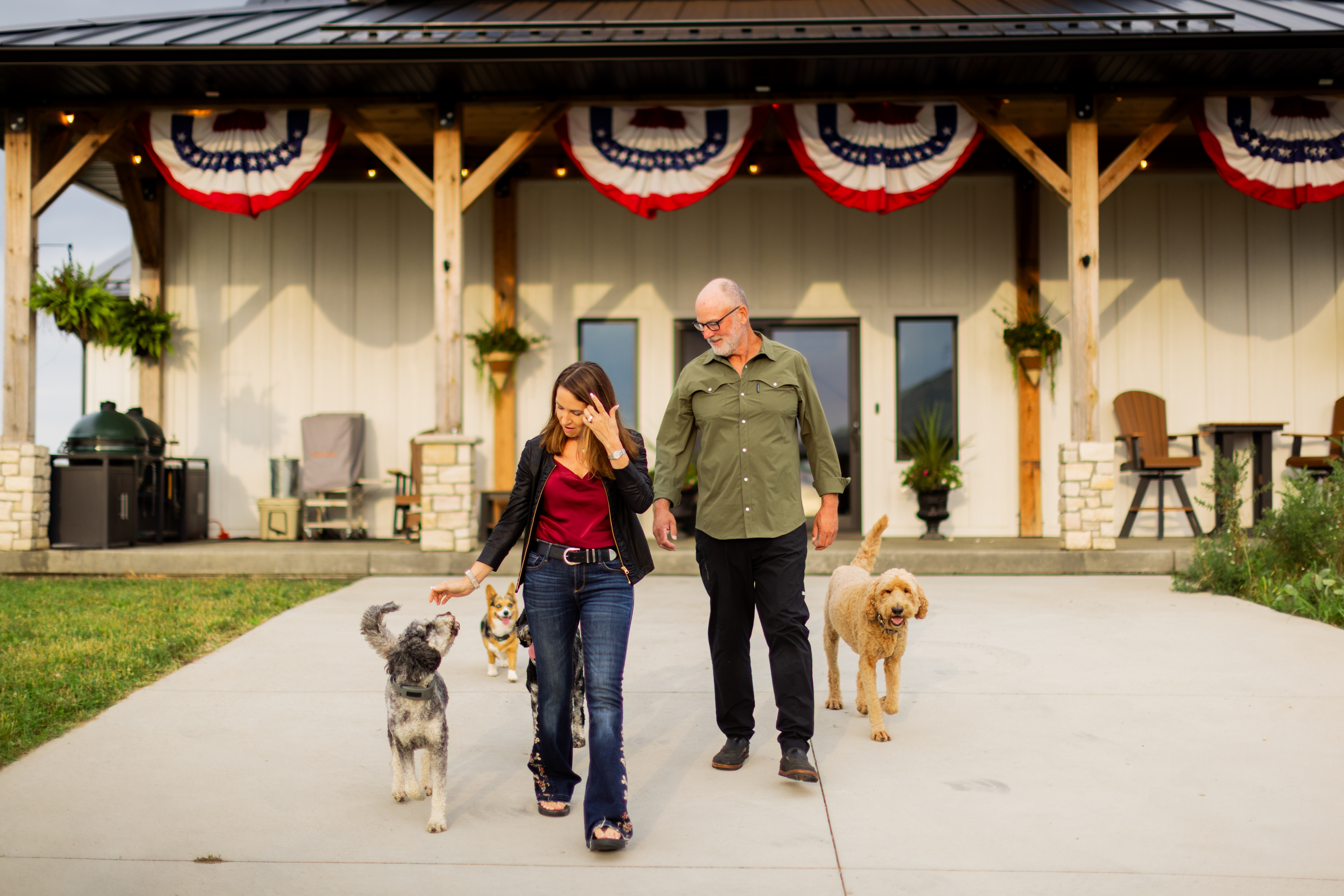 A couple walking with four dogs in front of house