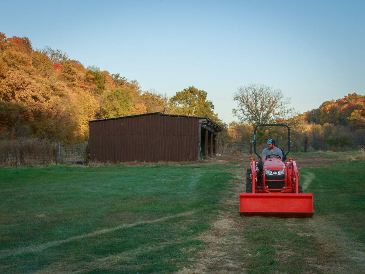Man on an orange tractor driving across grass