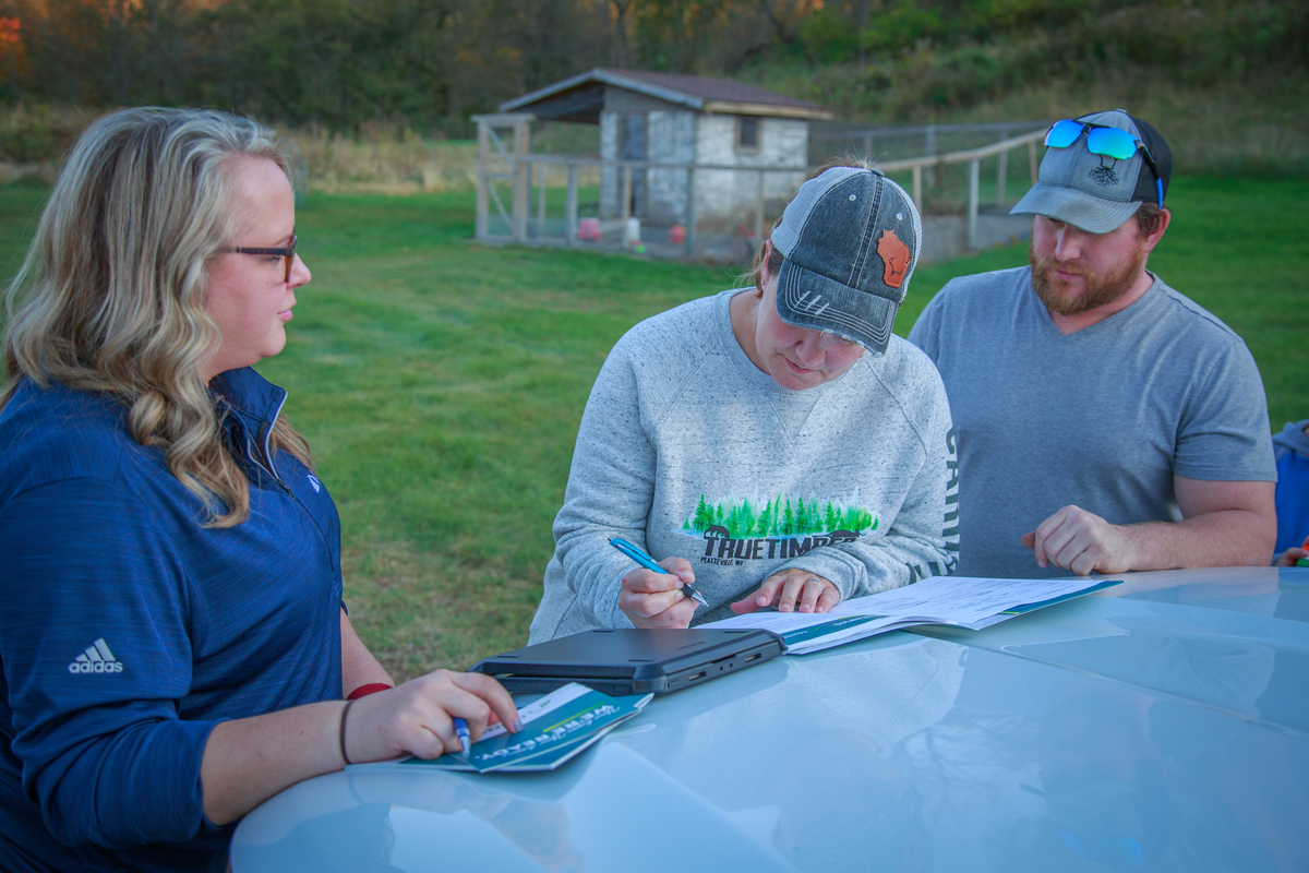 couple signing loan conversion on hood of truck