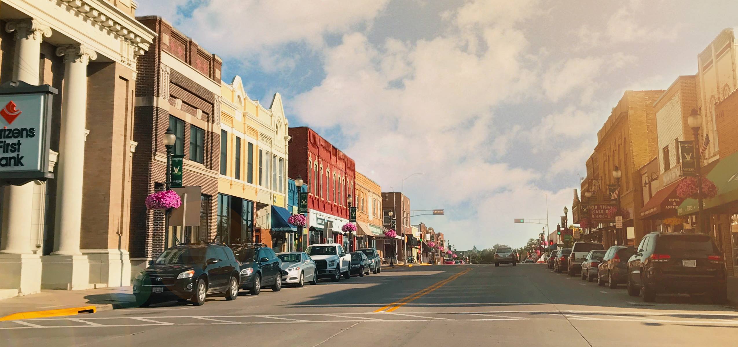 Main Street in downtown Viroqua, Wisconsin with shops, cars and hanging flower baskets.
