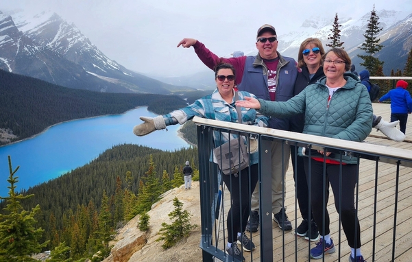 Family standing together outside a white farmhouse on a gravel driveway under cloudy skies.