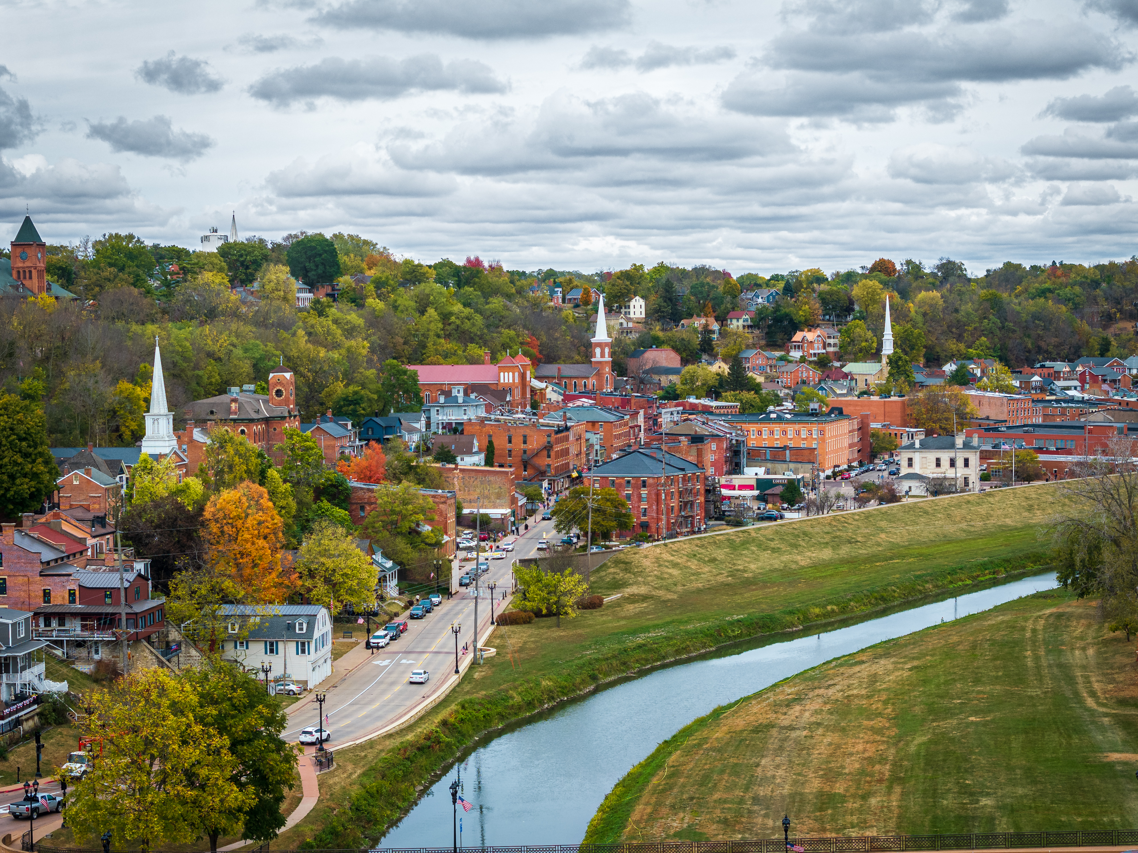 Aerial view of a historic river town with fall trees, church steeples and winding creek.