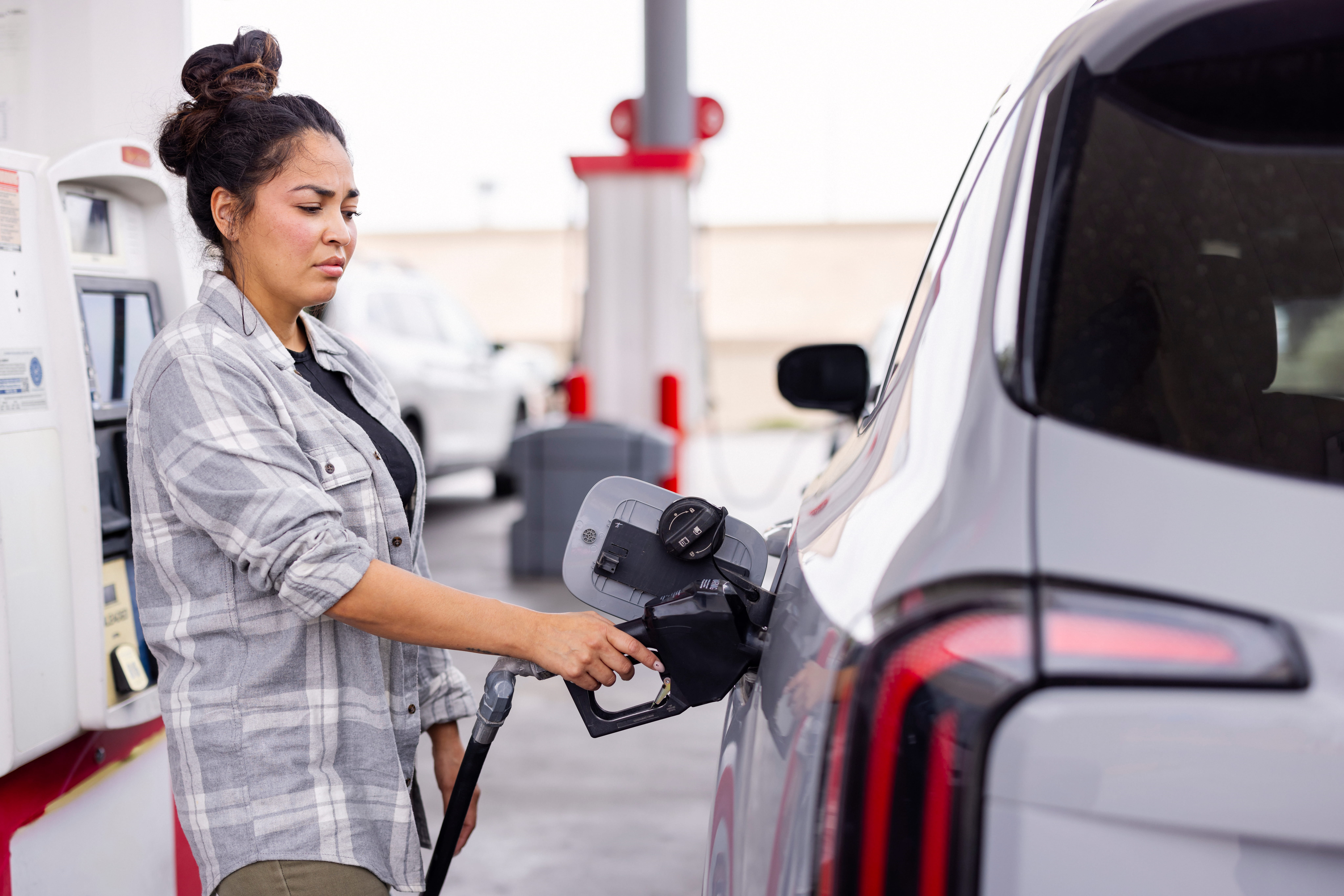 A woman pumps gas into her car.