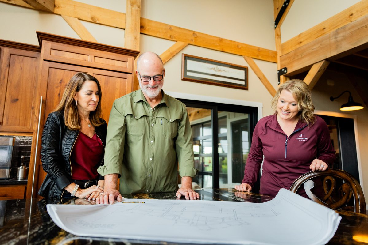 Couple reviewing home building plans with a Compeer Home loan officer at a table.